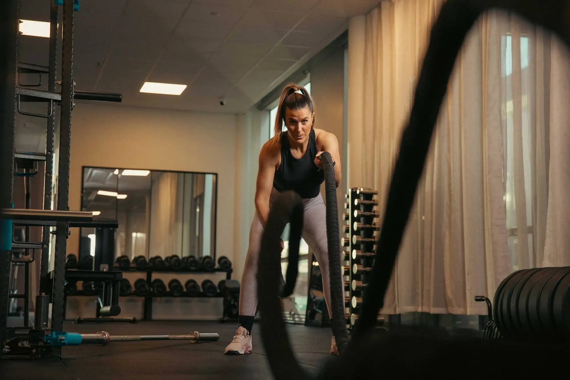 Kvinna tränar med tunga rep i ett gym