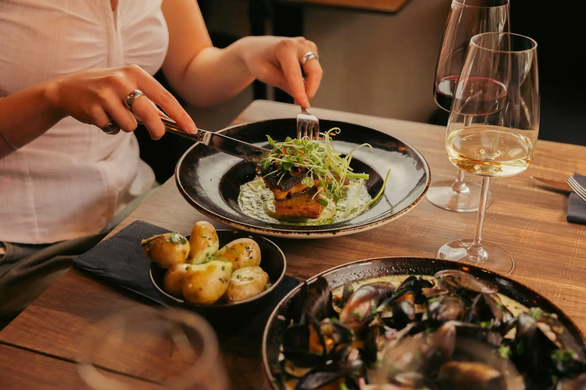 Middagsbord med tallrik, vitt vin och musslor